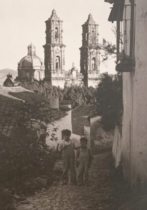 A black and white photo of two children in front of some buildings.