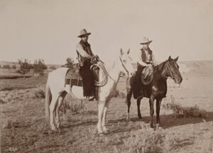 Two men on horseback in a field.