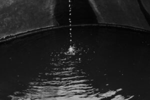 A black and white photo of water pouring out of a pipe.