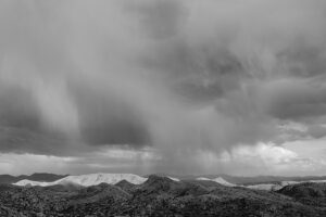 A black and white photo of the sky with rain coming in.