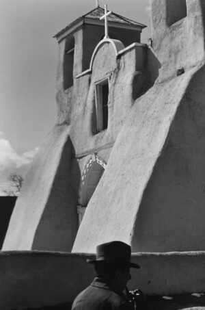 A black and white photo of a building with a person standing on it.