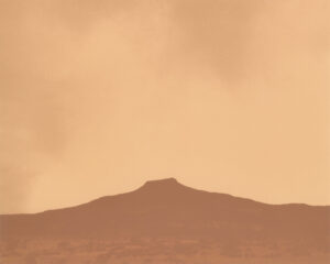 A brown sky with some clouds and mountains