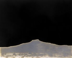 A black sky with some clouds and a mountain