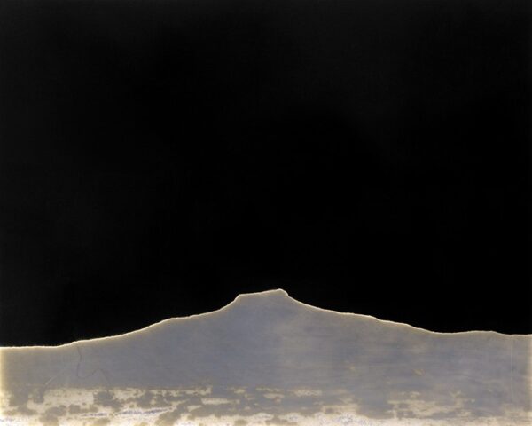 A black sky with some clouds and a mountain