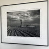 A black and white photo of a field with a windmill in the background.