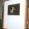 A framed picture of a woman sitting on the ground.