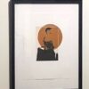 A framed picture of a man sitting on top of a chair.