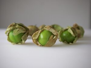 A group of green apples sitting in the middle of a white table.