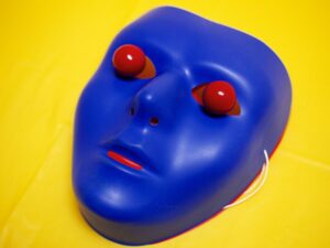 A blue mask with red eyes on yellow background.