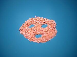 A pile of pink rice sitting on top of a blue surface.