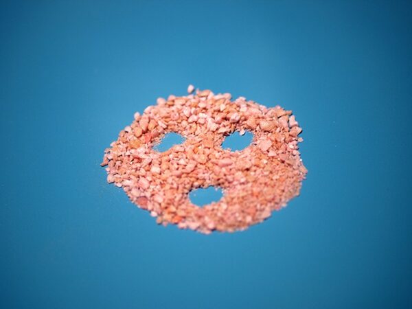 A pile of pink rice sitting on top of a blue surface.