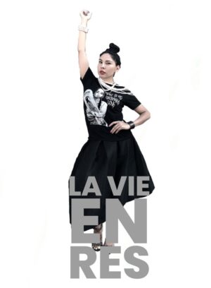 A woman in black shirt and skirt holding up her hand.
