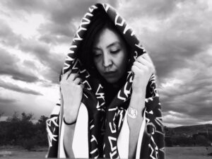 A woman wrapped in a blanket with a hood over her head.