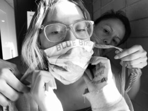 Two women are brushing their teeth with a face mask.