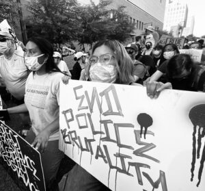 A group of people holding signs and wearing masks.