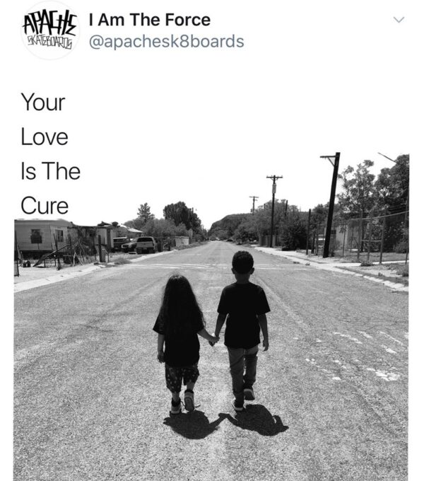 Two people holding hands while walking down a street.