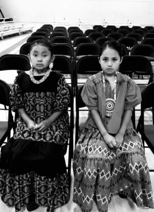 Two young girls sitting in rows of chairs.