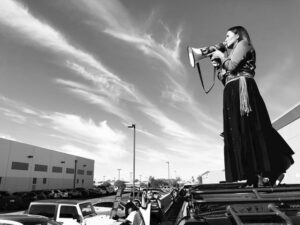 A woman holding a megaphone in the middle of a parking lot.