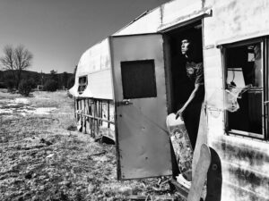 A woman standing in front of an old trailer.