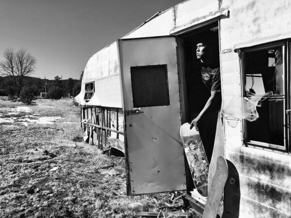 A woman standing in front of an old trailer.