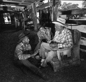 Three men sitting in a chair and talking.