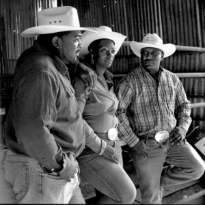 Three men in cowboy hats and jeans standing next to each other.
