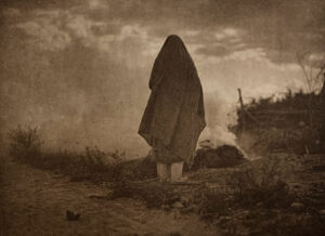 A person standing in the desert with their head down.