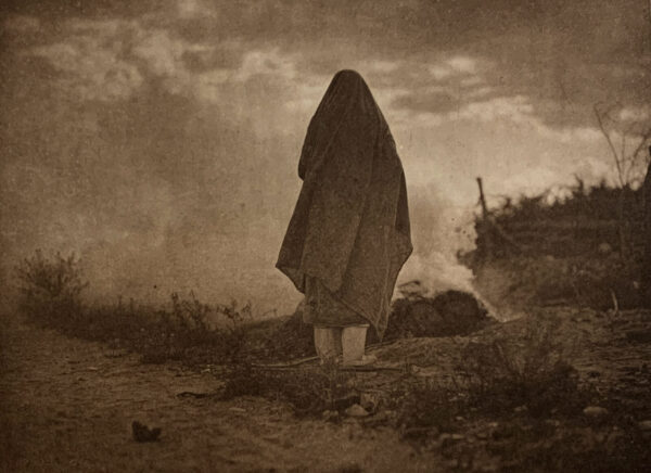 A person standing in the desert with their head down.