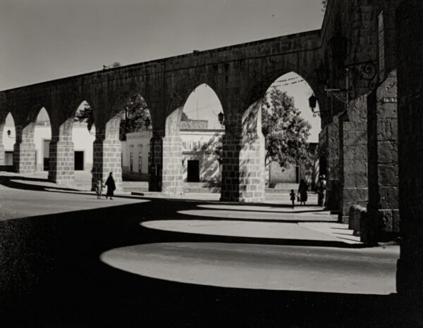 A black and white photo of an old stone bridge.