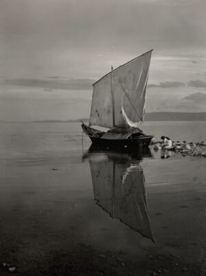 A boat floating on top of water near other boats.