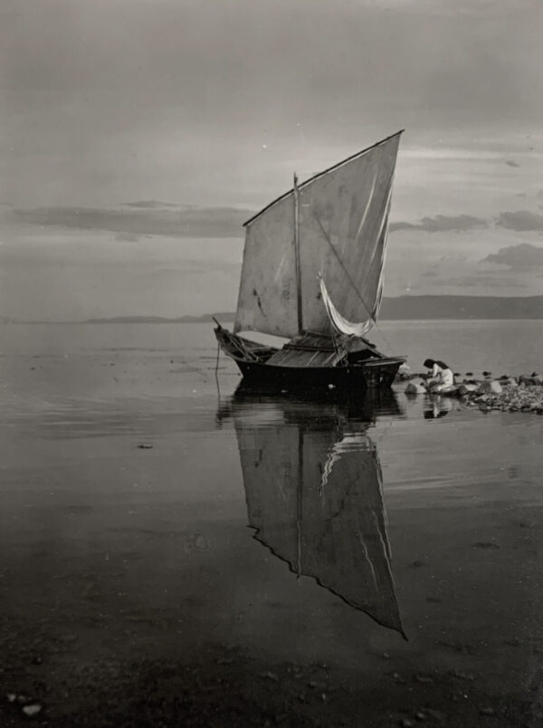 A boat floating on top of water near other boats.