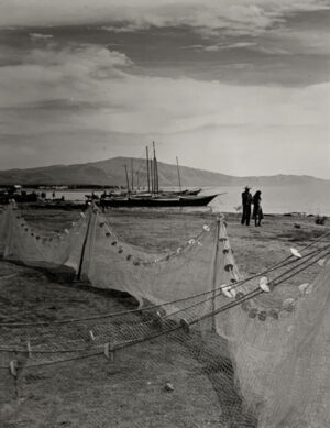 Two men standing on the beach near a boat.
