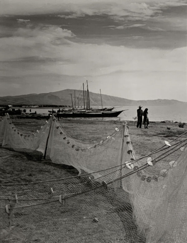 Two men standing on the beach near a boat.
