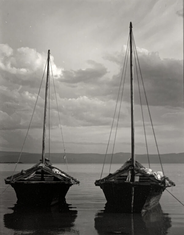 Two boats in the water with a cloudy sky above.