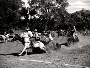A group of men riding horses in the dirt.