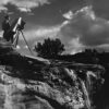 A man standing on top of a cliff with a camera.
