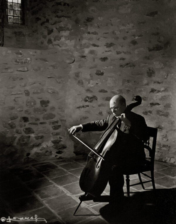 A man sitting in a chair holding a cello.
