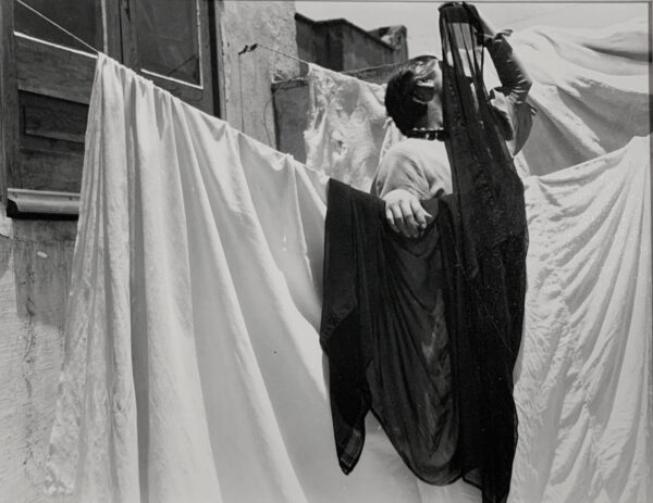 A woman hanging clothes on the line outside