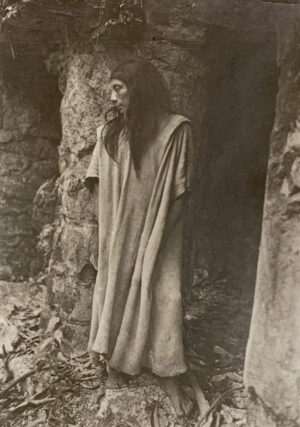 A person in a robe standing next to a tree.