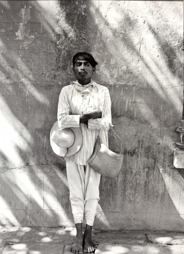 A man in white shirt holding two hats.
