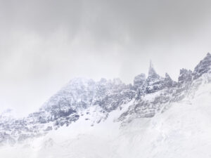 A mountain with snow on it and clouds in the sky.