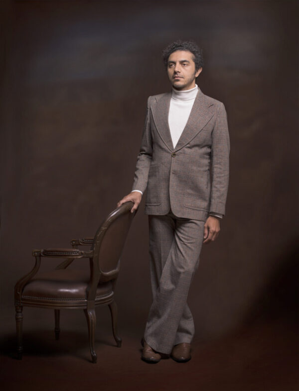 A man in a suit standing next to a chair.