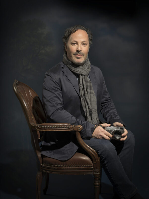A man sitting in a chair holding a camera.