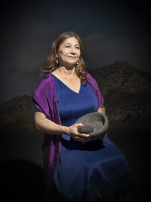 A woman in blue dress holding a hat.