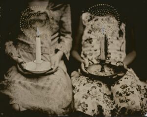 Two women holding candles in a basket.