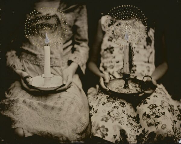 Two women holding candles in a basket.