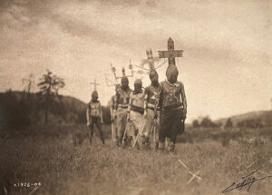 A group of men standing in the grass with crosses on their heads.