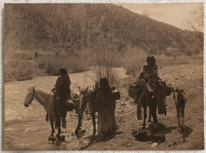 A group of people riding horses in the desert.