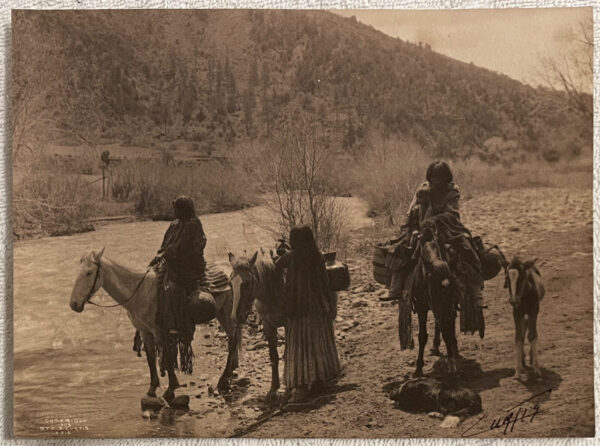 A group of people riding horses in the desert.