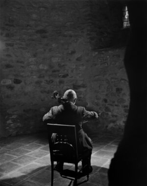 A man sitting in a chair playing the violin.